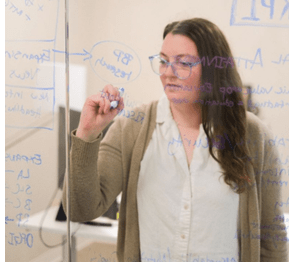 Employee from Slingshot brainstorms ideas on a glass board.